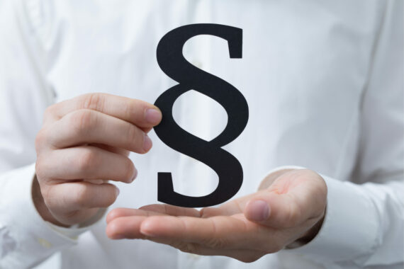 Person in weißem Hemd Hält das Paragraphen Zeichen